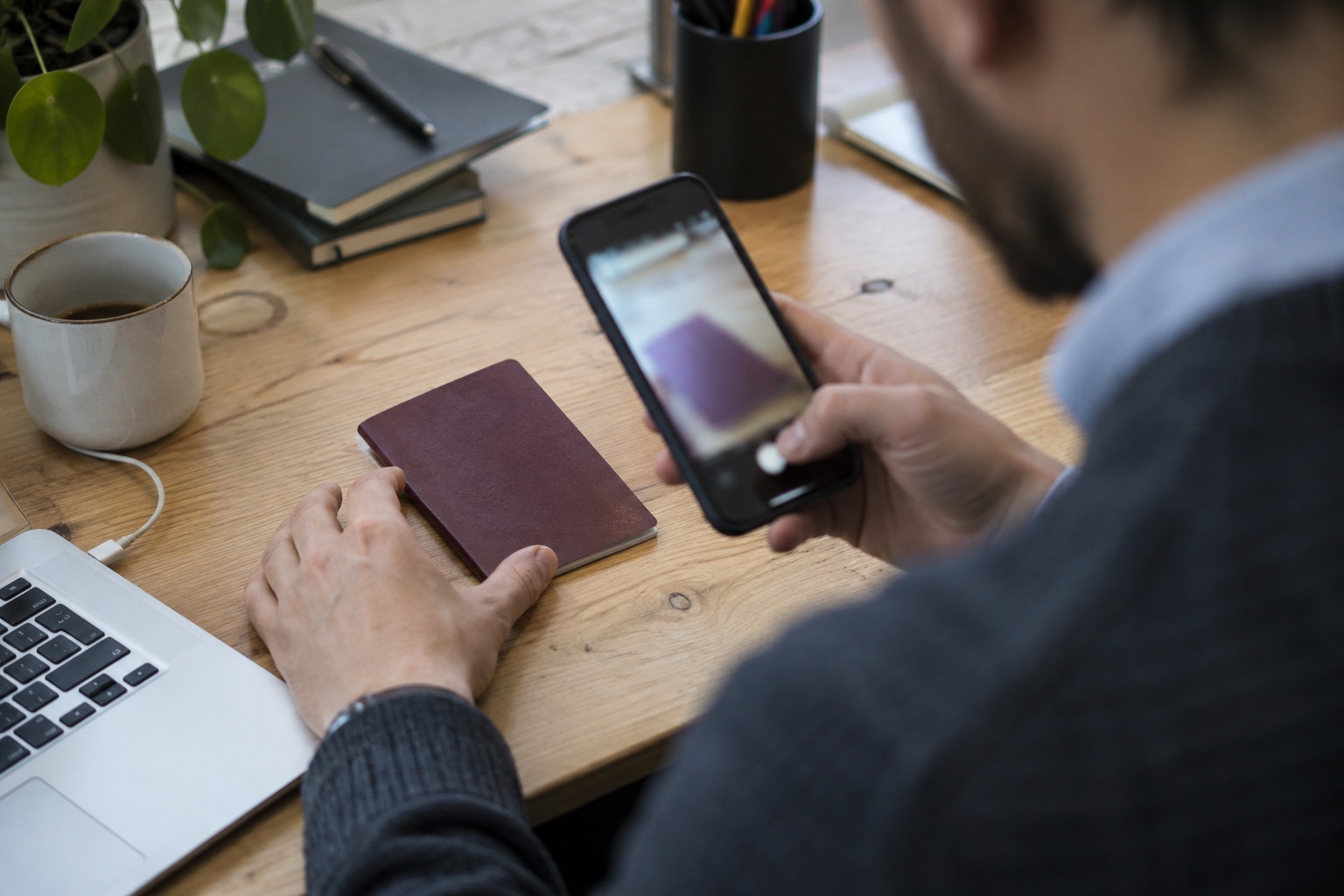 Company director using a smartphone to verify their identity with a passport at an office desk